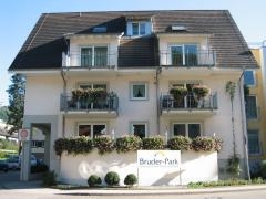 Gebäude mit drei Stockwerken. Im unteren eine Terrasse, oberhalb jeweils mit zwei Balkonen.