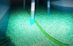 Wasserbecken aufbereitetes Wasser Raum mit vier Säulen, bis ca. zur Hälfte mit Wasser gefüllt, Muster der Fliesen schimmern durch das Wasser