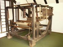 Webstuhl aus Holz, ca. 2 Meter hoch. Weiße Wolle ist eingesponnen