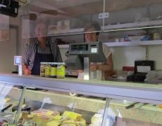 Zwei Verkäufer stehen in ihrem Verkaufswagen, davor die Auslagefläche mit Käse