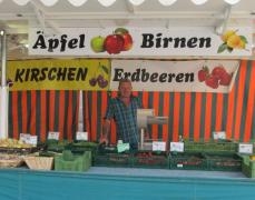 Ein Verkäufer steht hinter seinem Verkaufstisch mit Gemüse