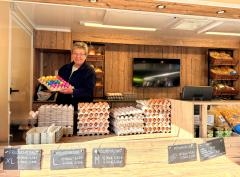 Im Vordergrund stehen Eier, Honig und Nudeln. Dahiner ein Verkäufer