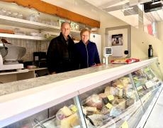 Zwei Verkäufer stehen in ihrem Verkaufswagen, davor die Auslagefläche mit Käse